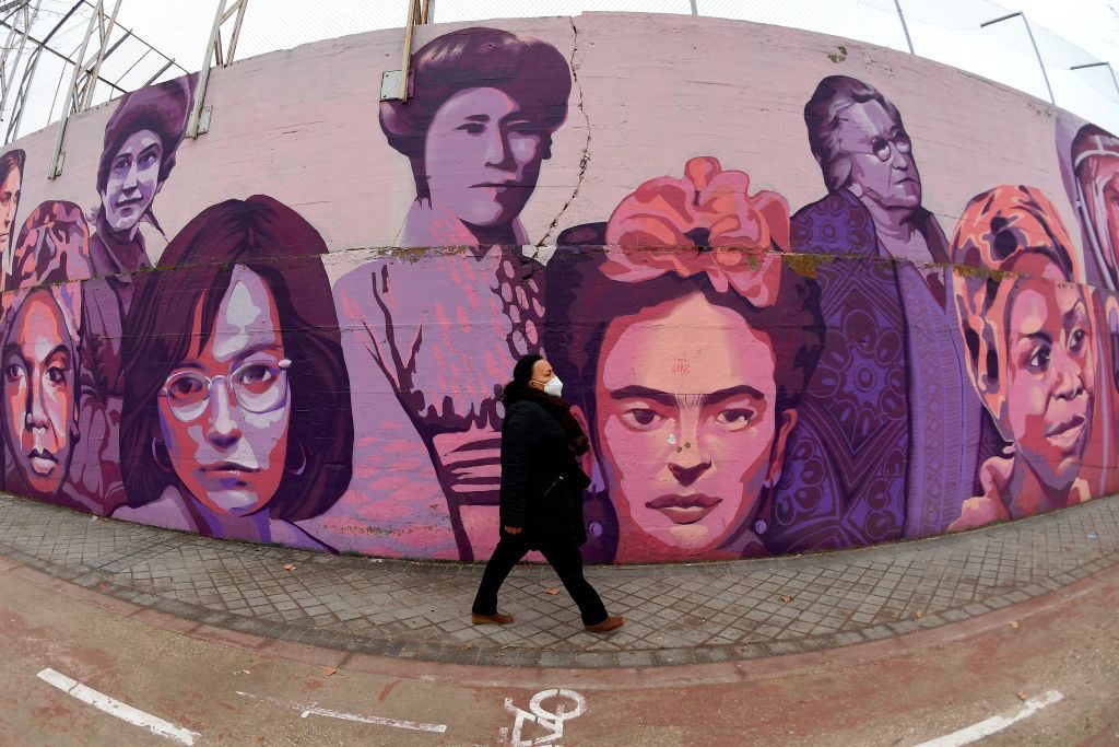 A person walks along a mural painting depicting sixteen outstanding women. Photo by Gabriel Bouys/AFP via Getty Images.