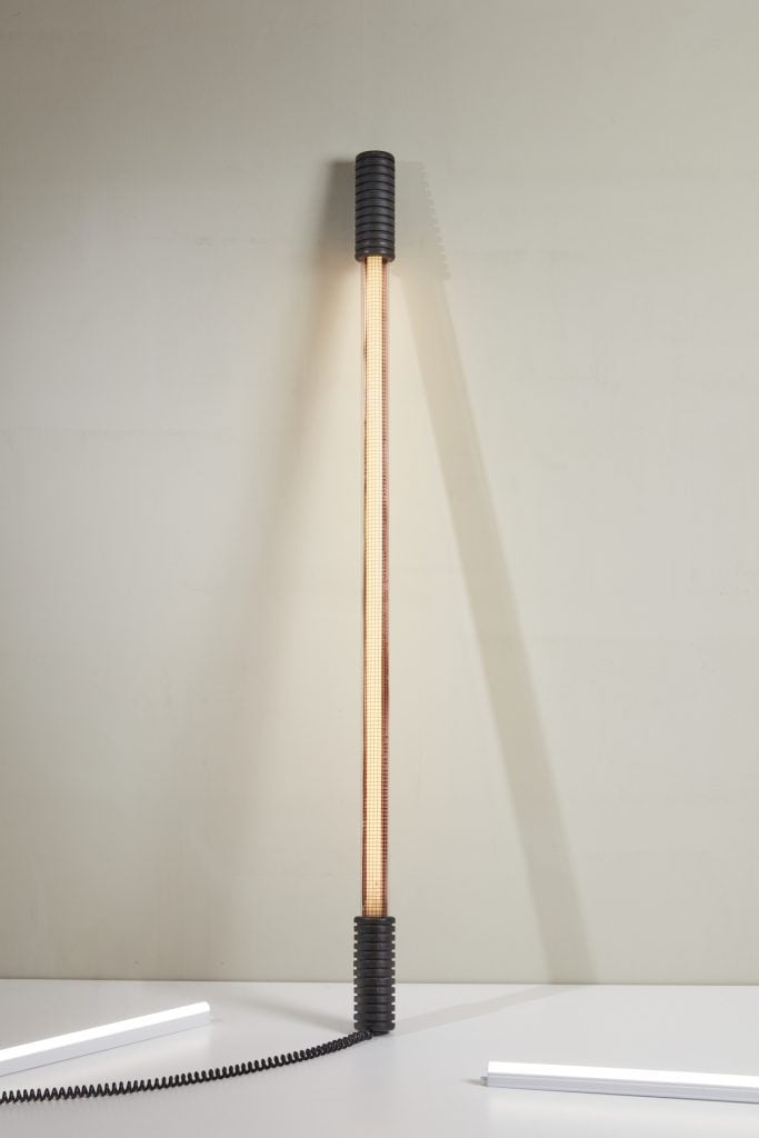 a tube light designer lamp leans against a white wall