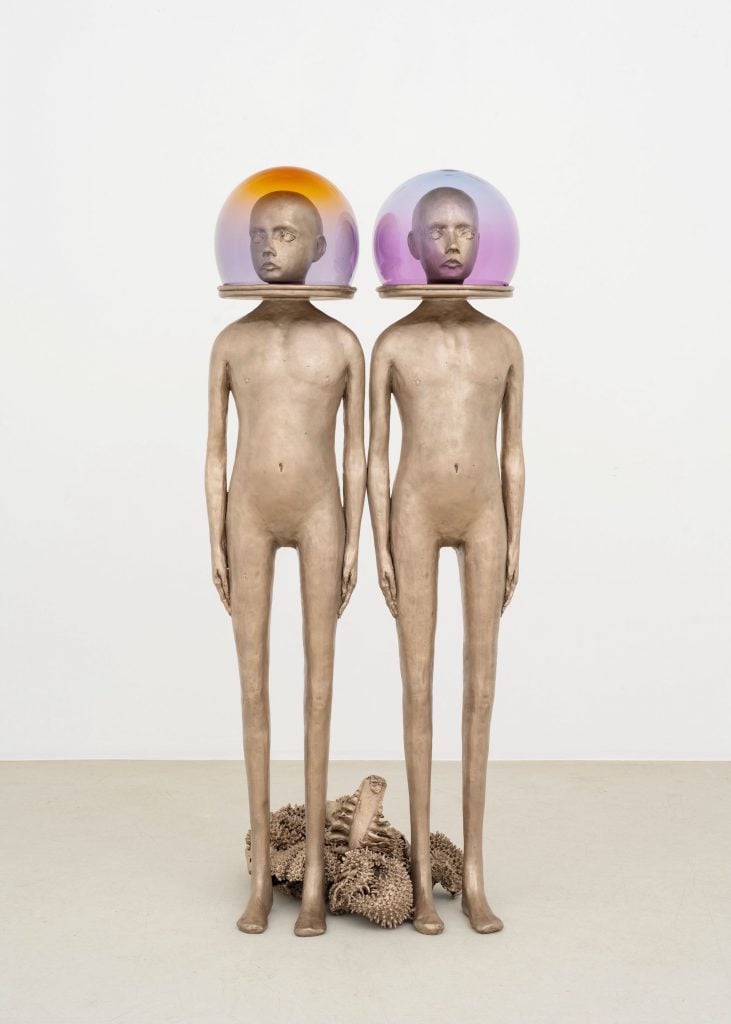 an image of two naked alien-like figures with glass globes over their heads