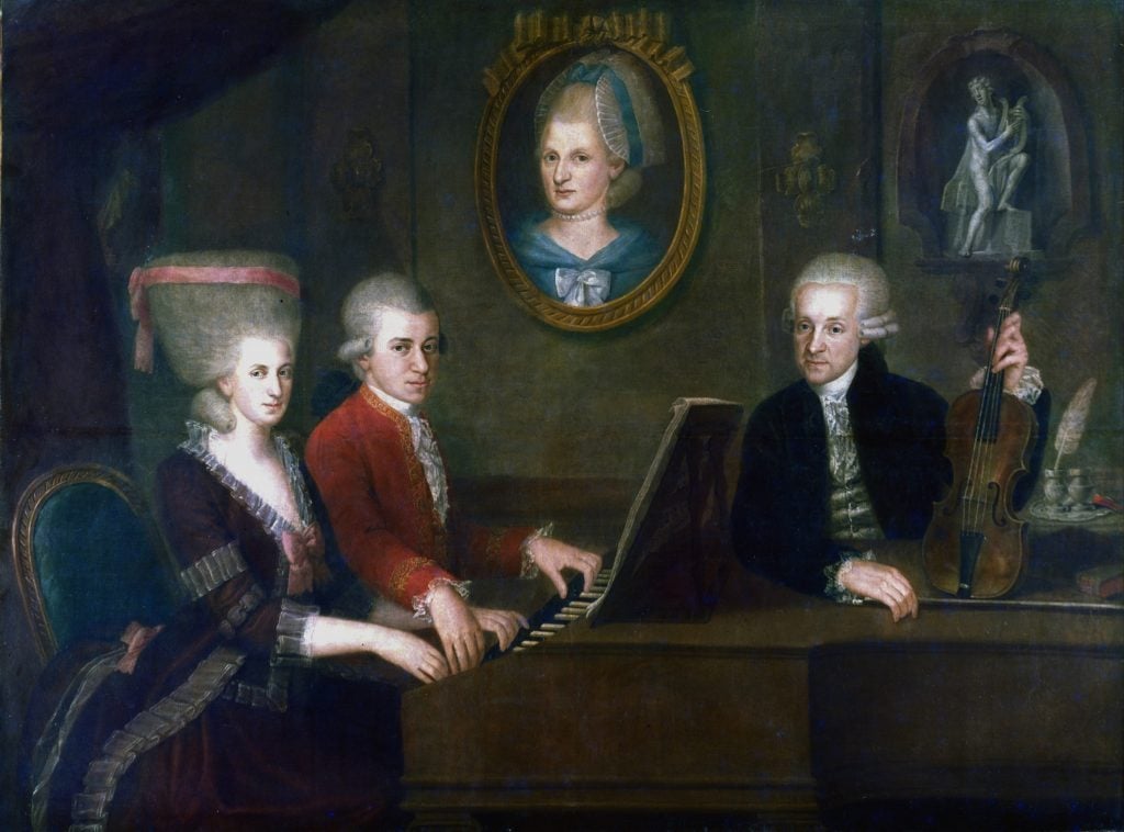 Painting of an elderly man standing beside a piano, while a young man and woman sit at the keyboard. A portrait of a woman hangs in the background.