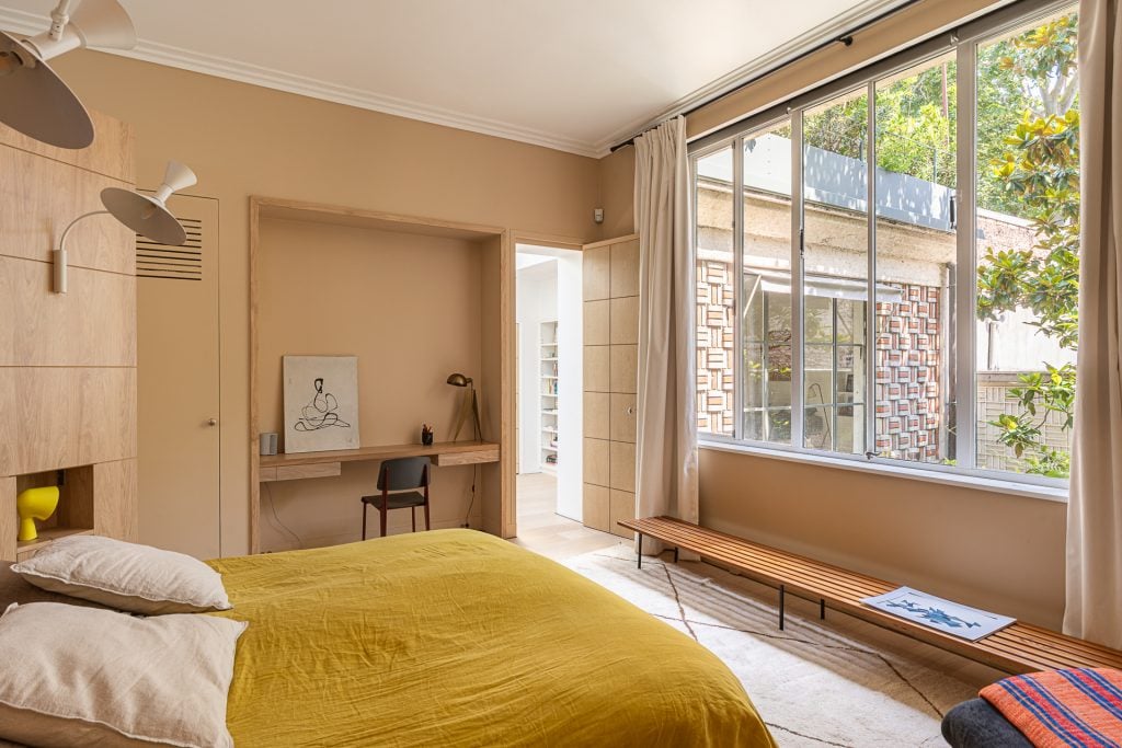 A bedroom in muted colors with a double bed facing a large window