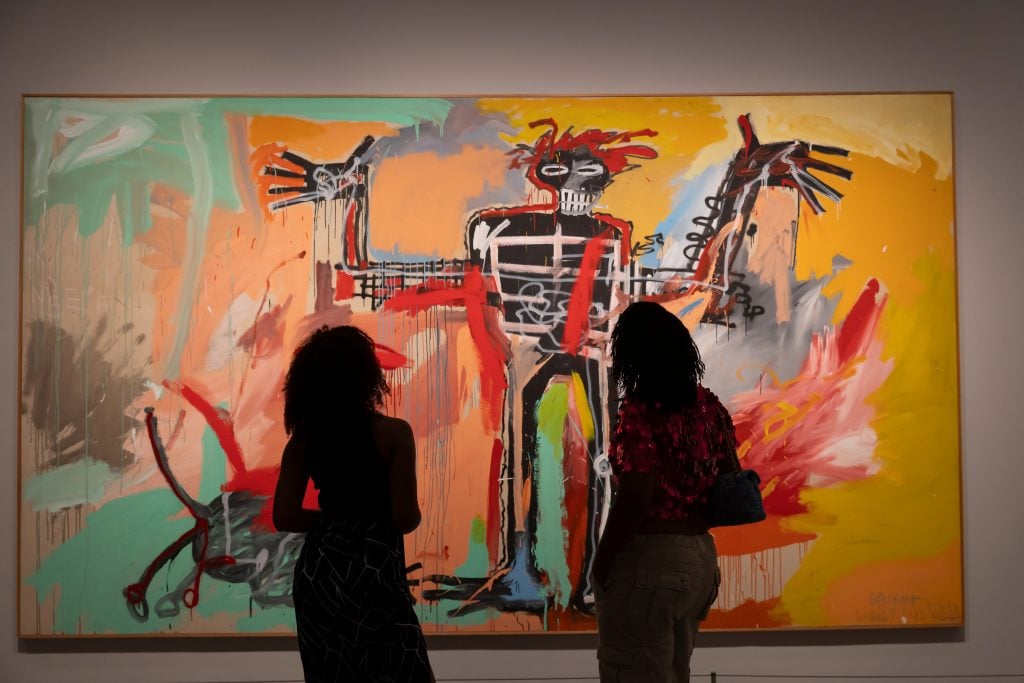 the silhouettes of two people can be seen against a dramatically lit and colorful painting by jean michel basquiat