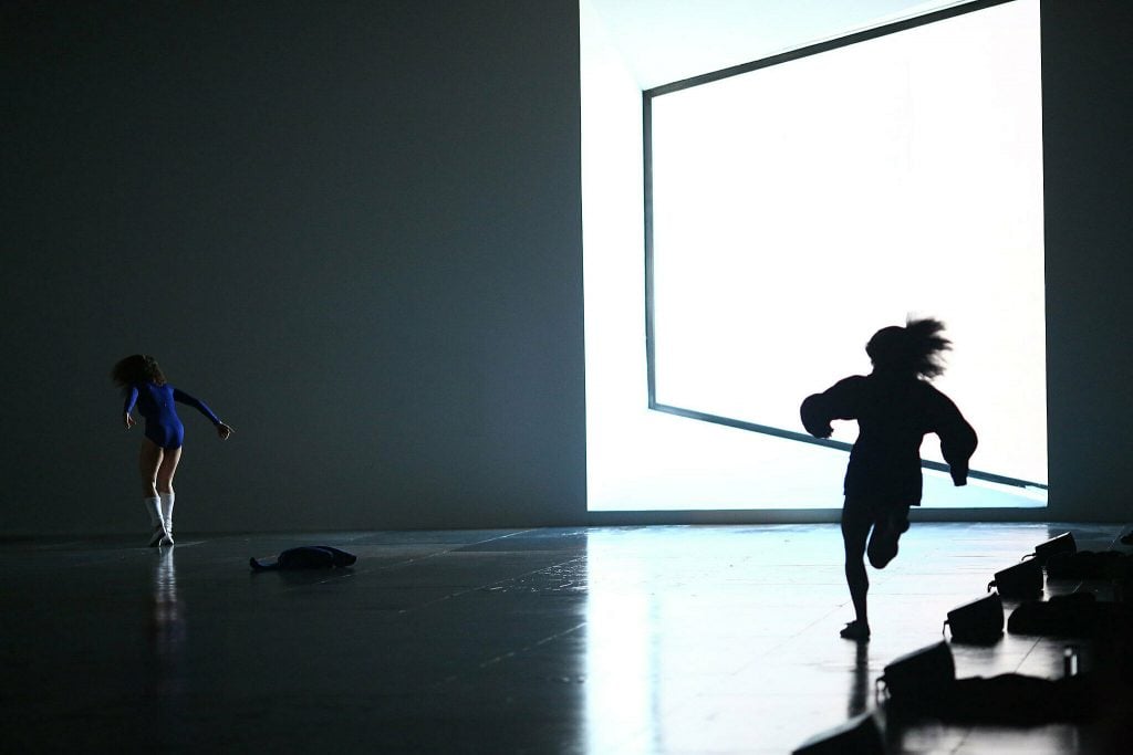 a view of dramatic modern dancing set against gleaming light on stage 