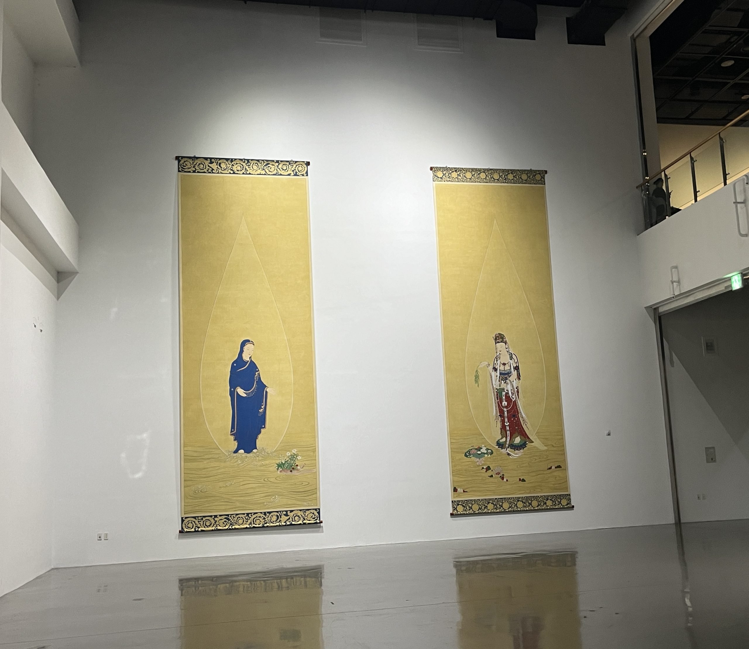 Two tall paintings with golden backgrounds depict, respectively, a man and a woman