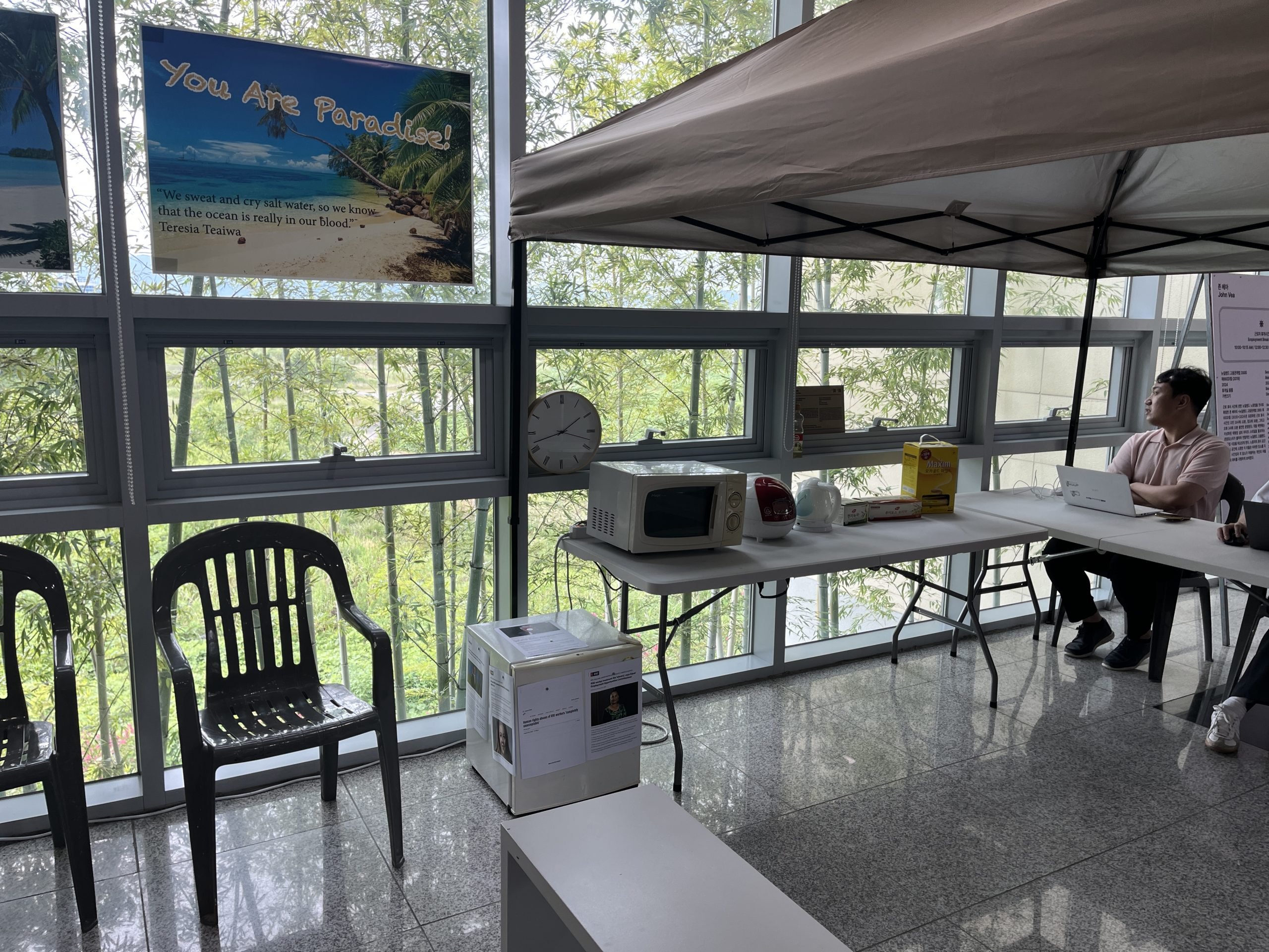 A table holds a microwave and basic kitchen materials underneath a little tent