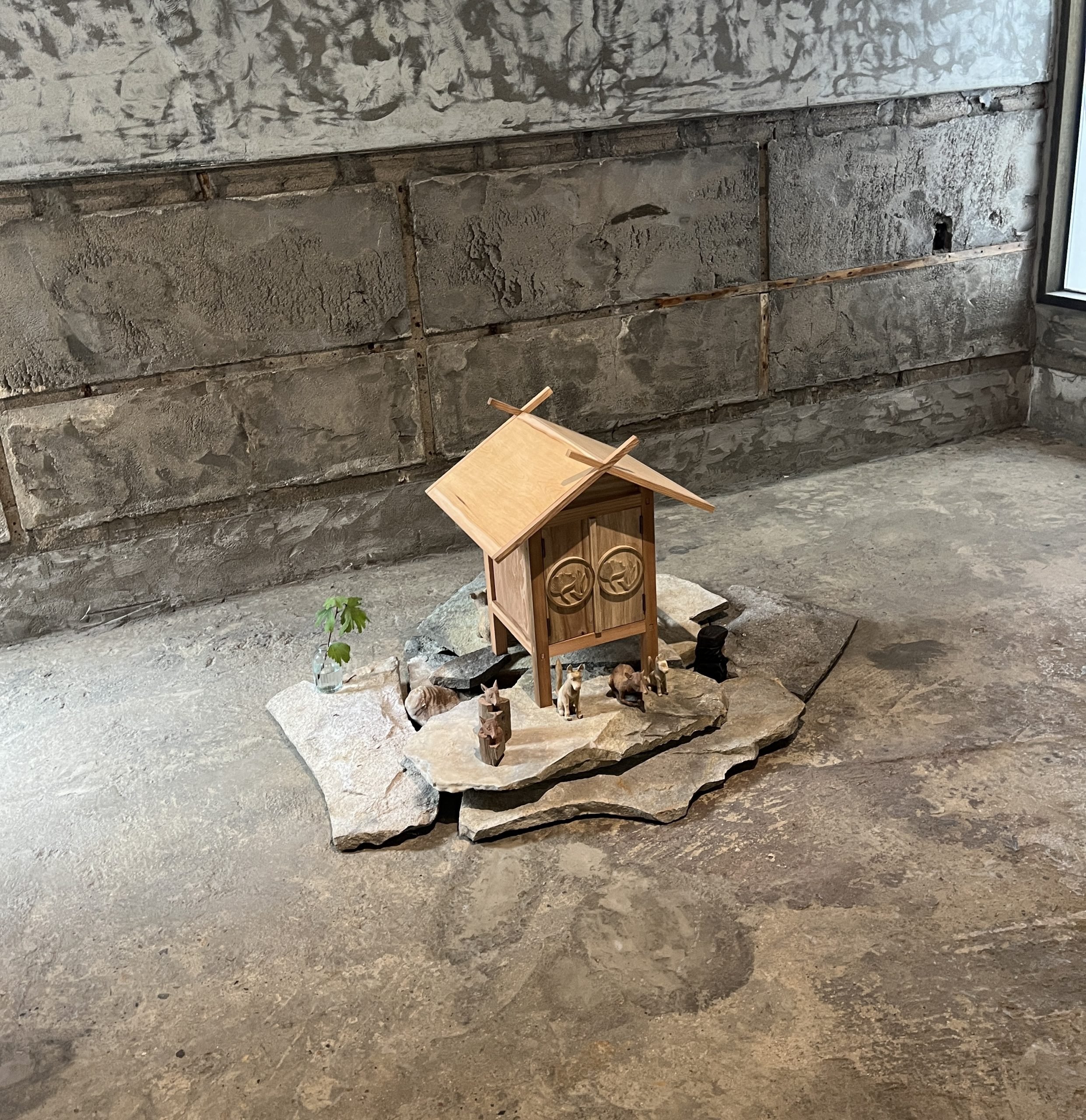 A small wooden house sits on a cement floor