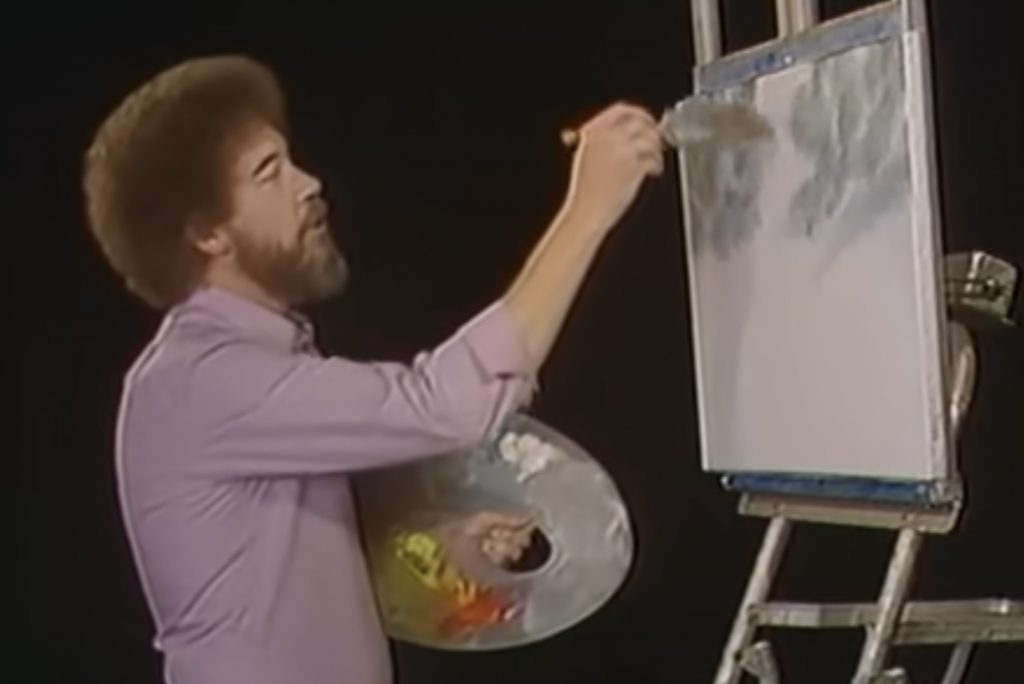 A photograph of Bob Ross beginning a painting with grey clouds.