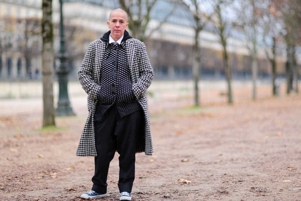 A photo of a stylishly dressed woman with a shaved head