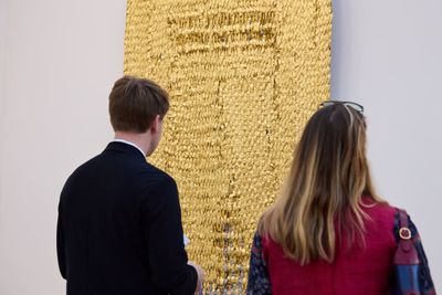 Fair goers examine Olga de Amaral's Viento Oro (2014). Linen, gesso, acrylic, Japanese paper and gold leaf. 225 x 120 cm. Photo