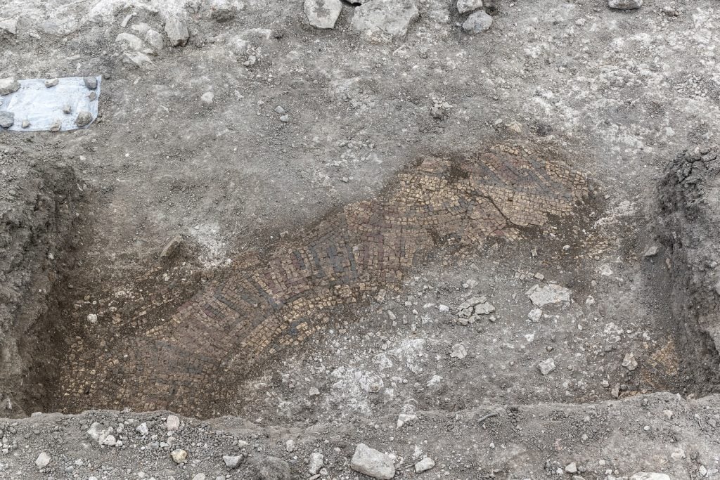 the remains of a mosaic partially buried beneath dirt