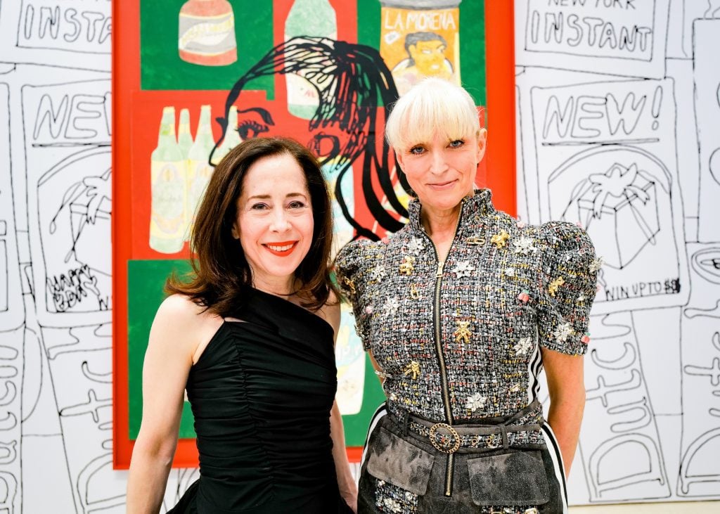 Two well-dressed women standing in front of a colorful artwork