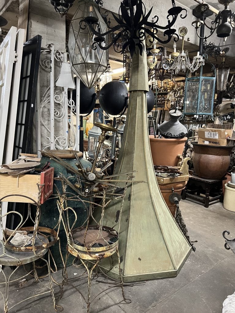 A vintage shop full of assorted antiques, including wire chairs and hanging light fixtures.