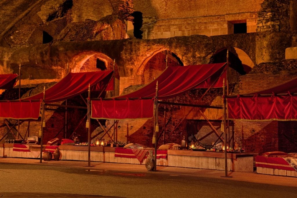 a brown-hued photograph of lush red draped beds