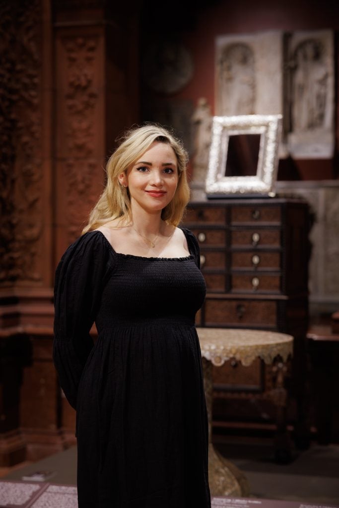 a woman stands in a historical museum tableau 