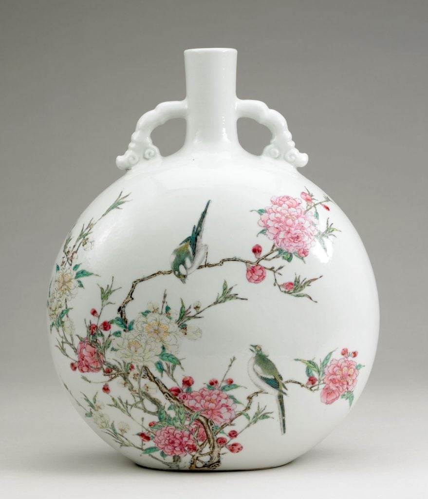 a ceramic flask that is white but covered with pastel coloured floral decorative elements