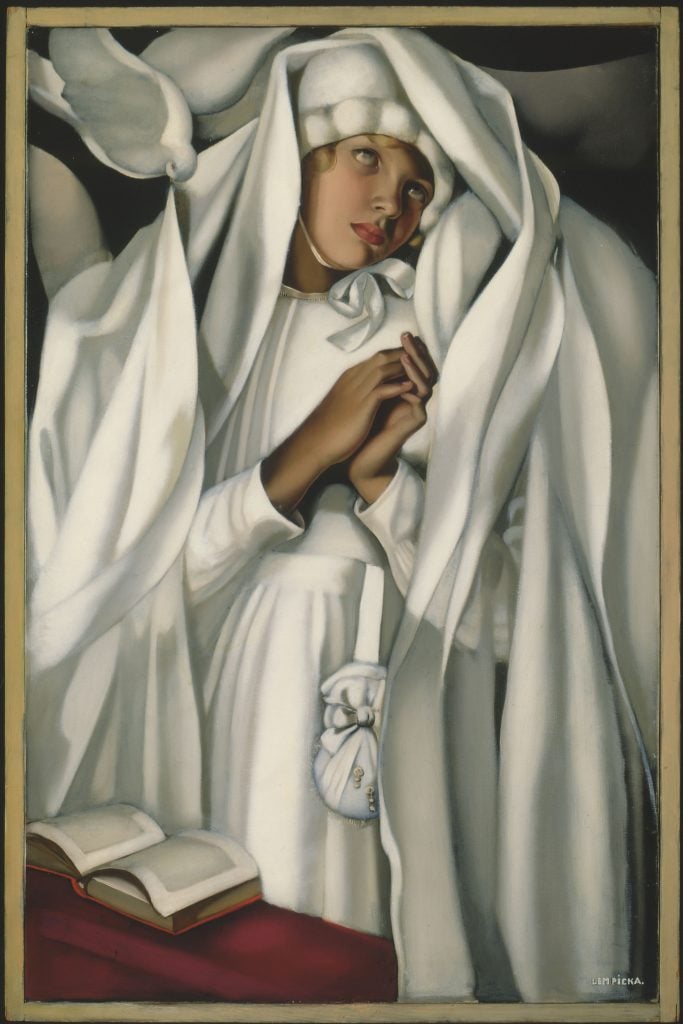 A painting of a young woman dressed in angelic white with praying hands reading a book that appears to be the bible.