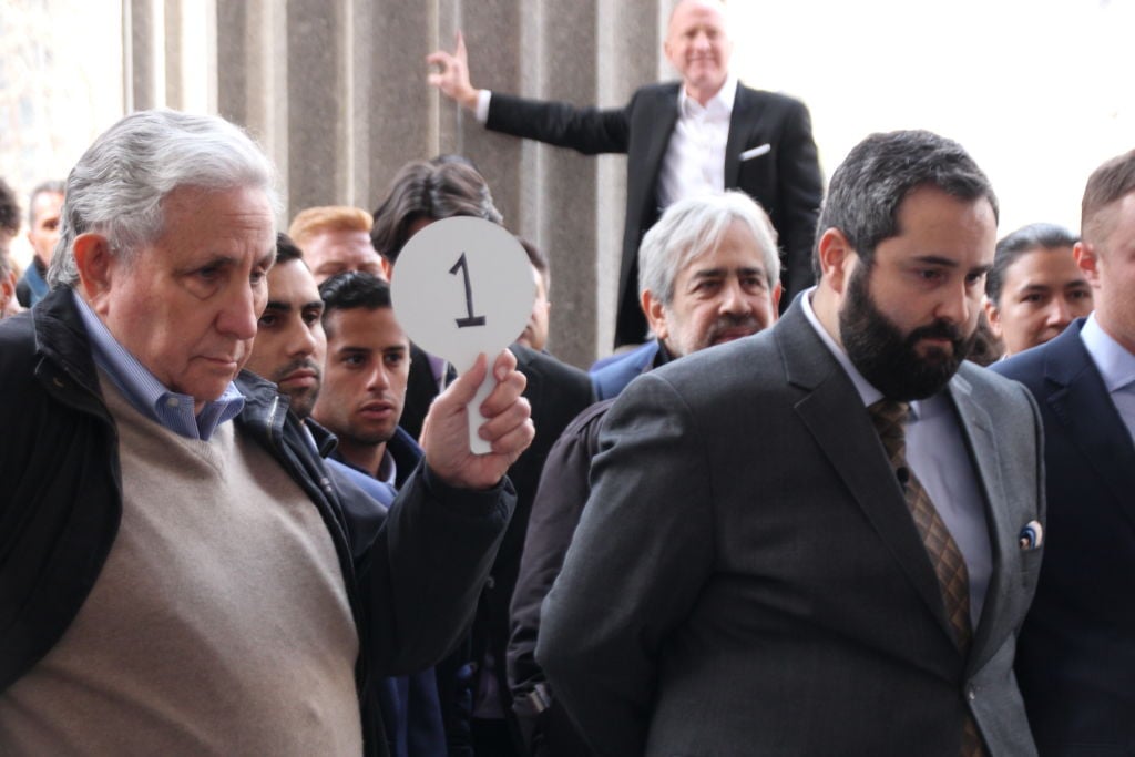 a group of men hold bidding paddles