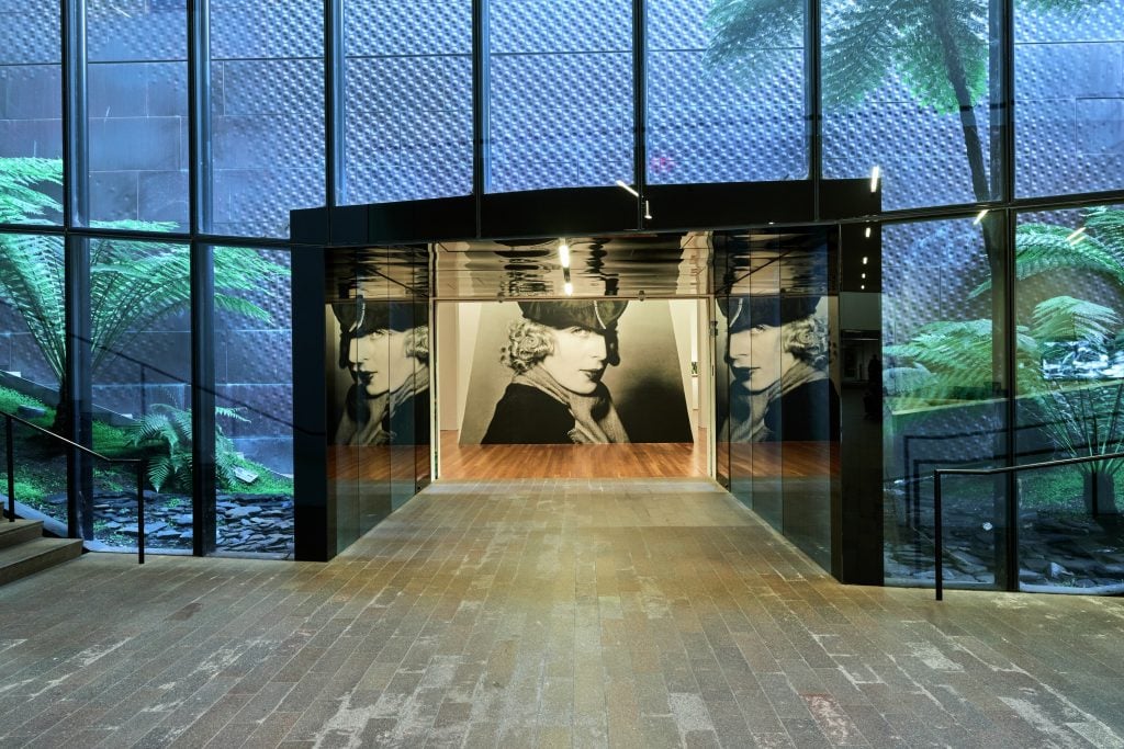 A photograph of the artist Tamara de Lempicka at the entrance to an exhibit of her work at the de Young Museum in San Francisco