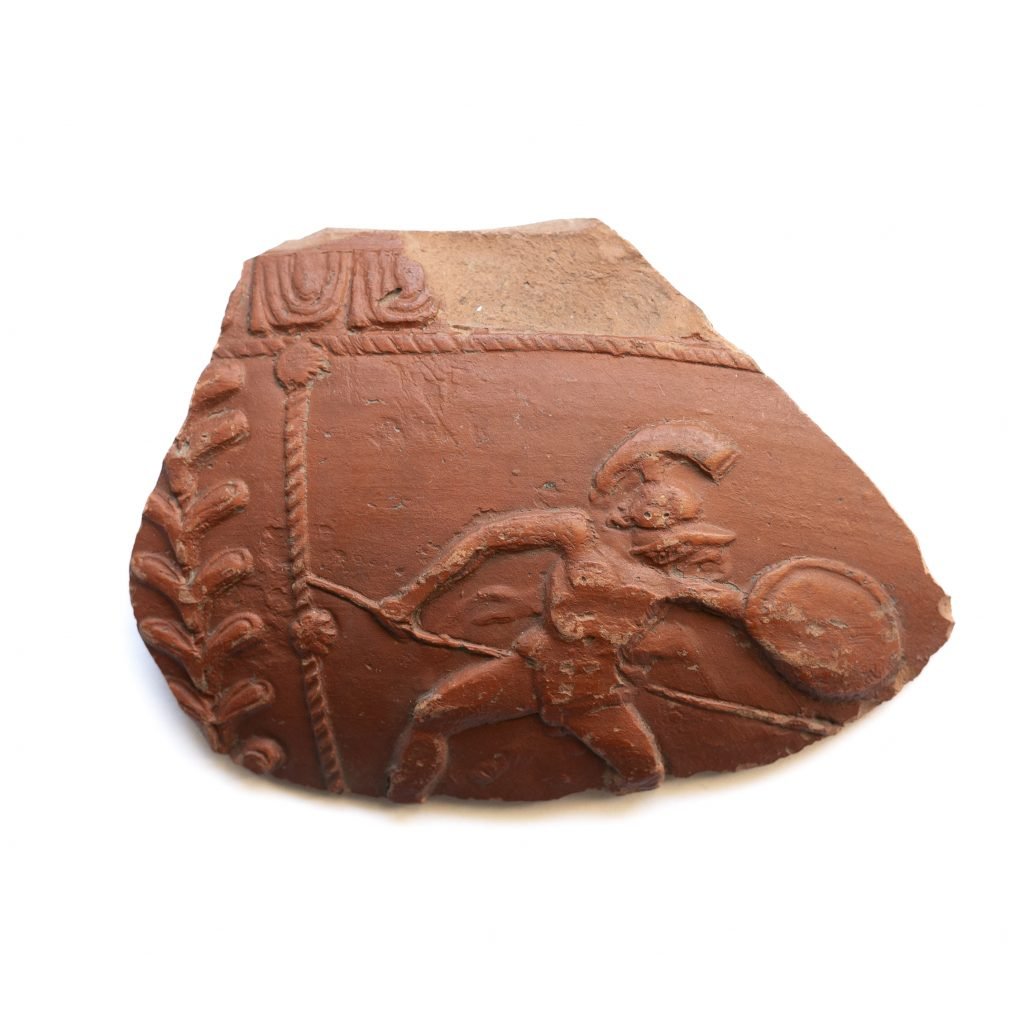 a piece of reddish pottery which shows a gladiator on