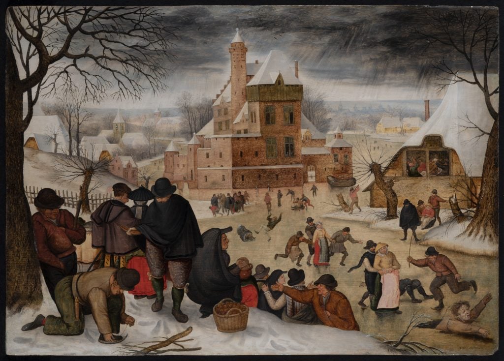 A winter landscape painted by Pieter Brueghel the Younger showing a group of revelers in the foreground and a crowd of people skating on a pond in the background against a large castle.