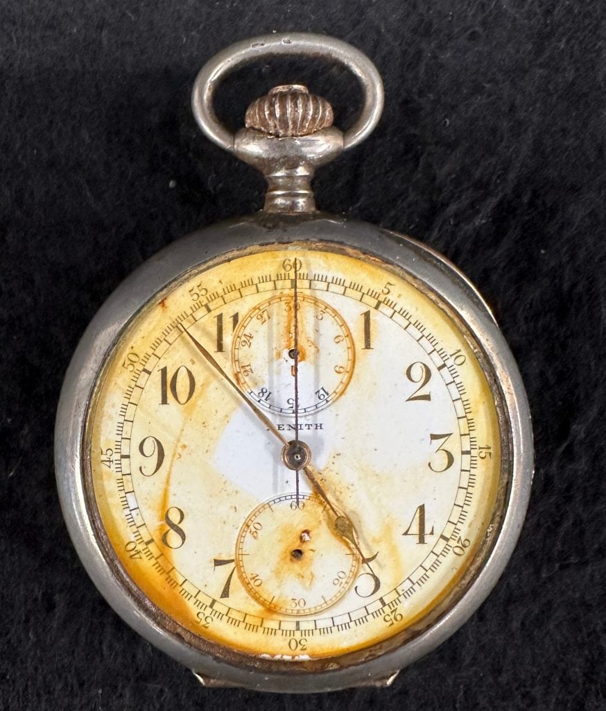 a very old and damaged looking pocket watch with stains and that doesn't work anymore but shows the time 4:55