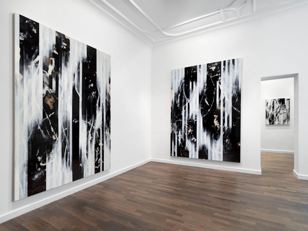 black and white paintings hang in a gallery