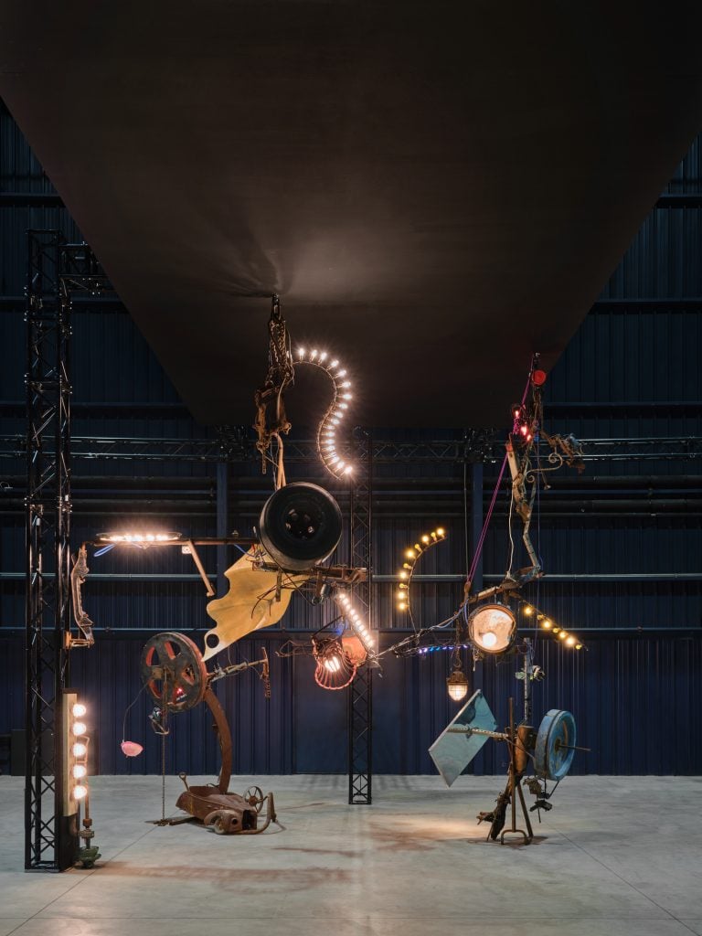 an industrial sculpture has lightbulbs and is illuminated 