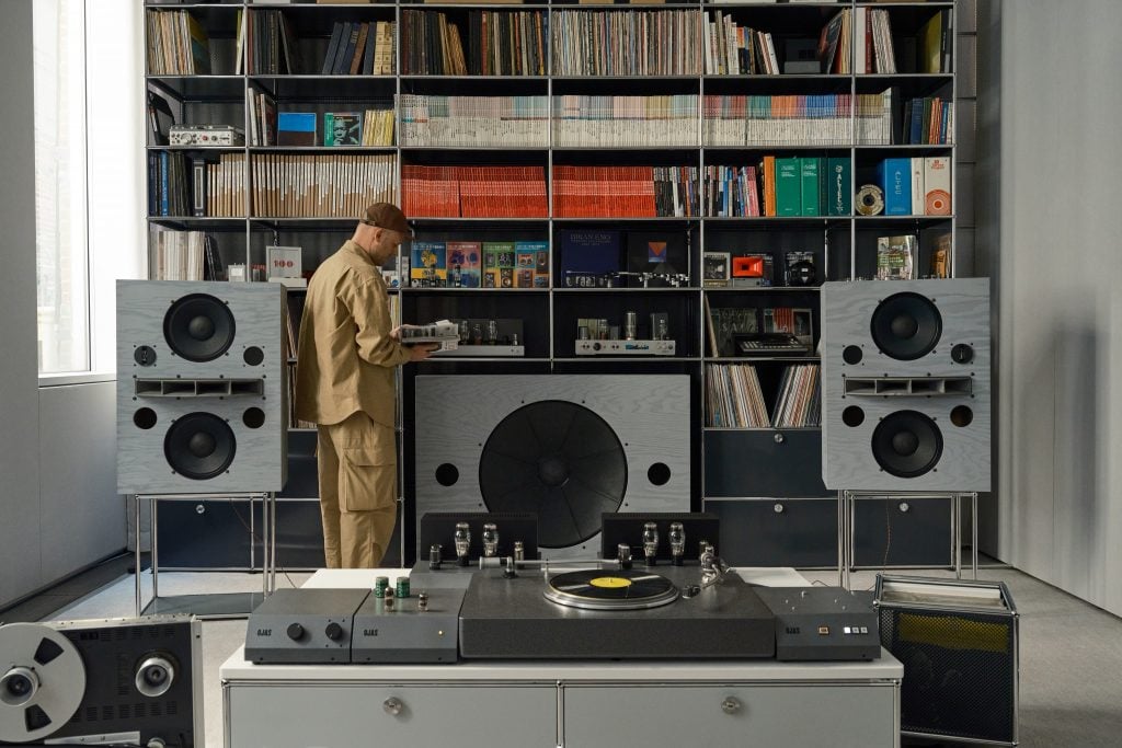 a man stands in front of enormous speakers 