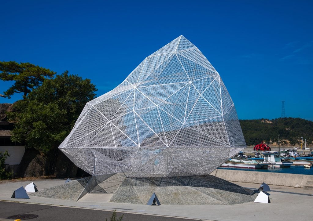 a wiry iceberg architectural pavilion is on a concrete platform 