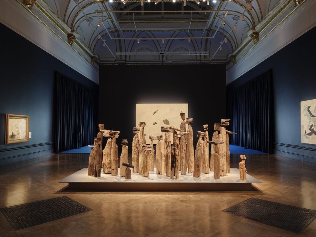 an installation of driftwood sculptures in a blue gallery