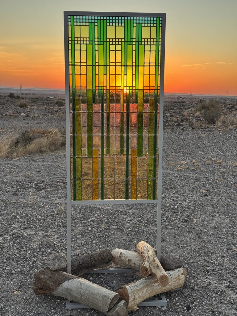 a glass art piece has the sun setting bnehid it 