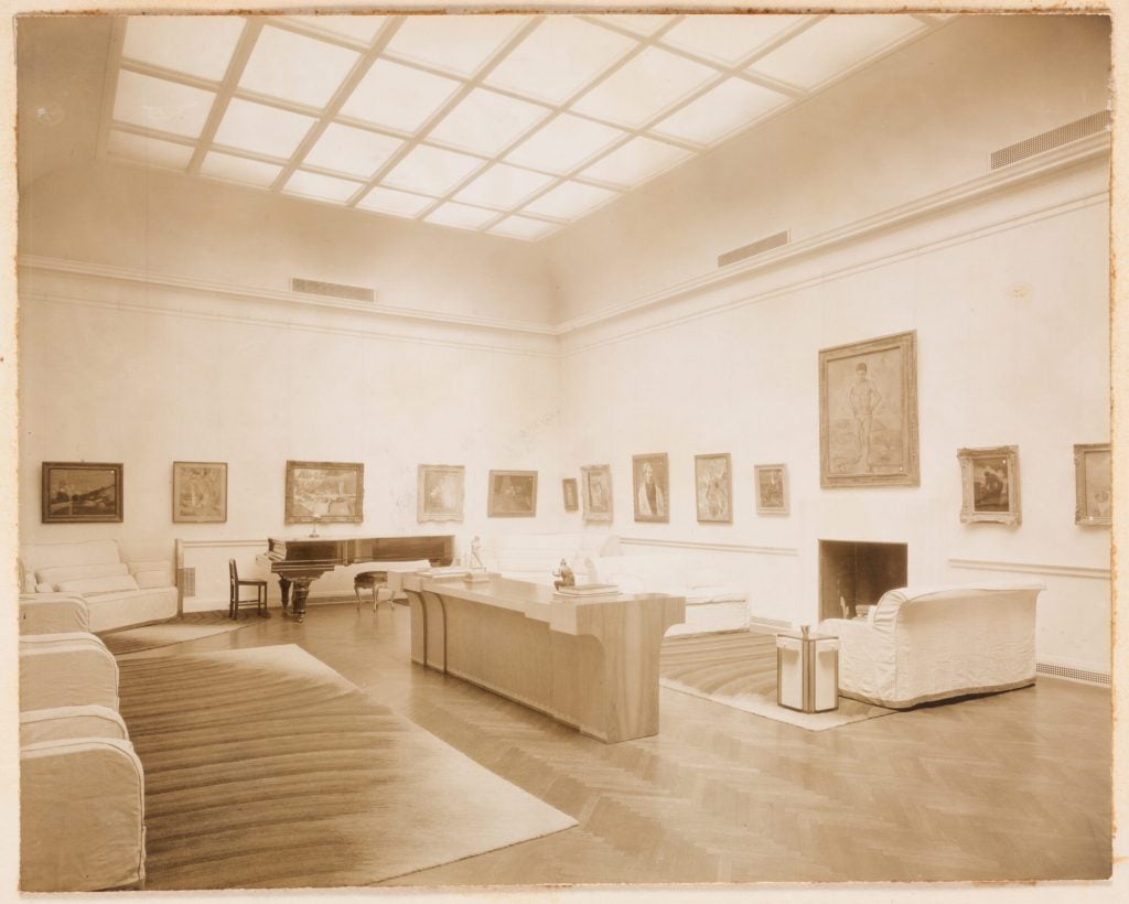 a sepia toned photo of an ornate lift room surrounded by modern art and modernist furniture 