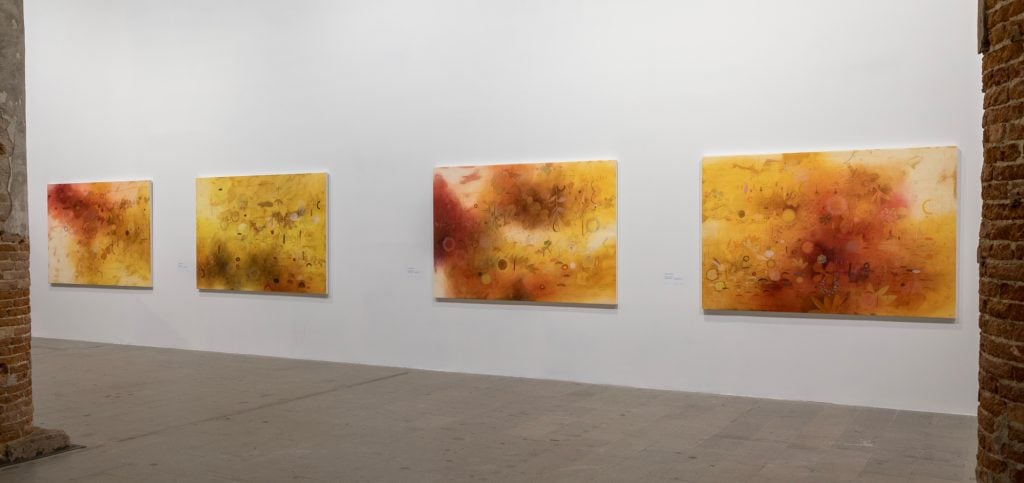 a suite of abstract paintings on a white wall in tones of orange and yellow