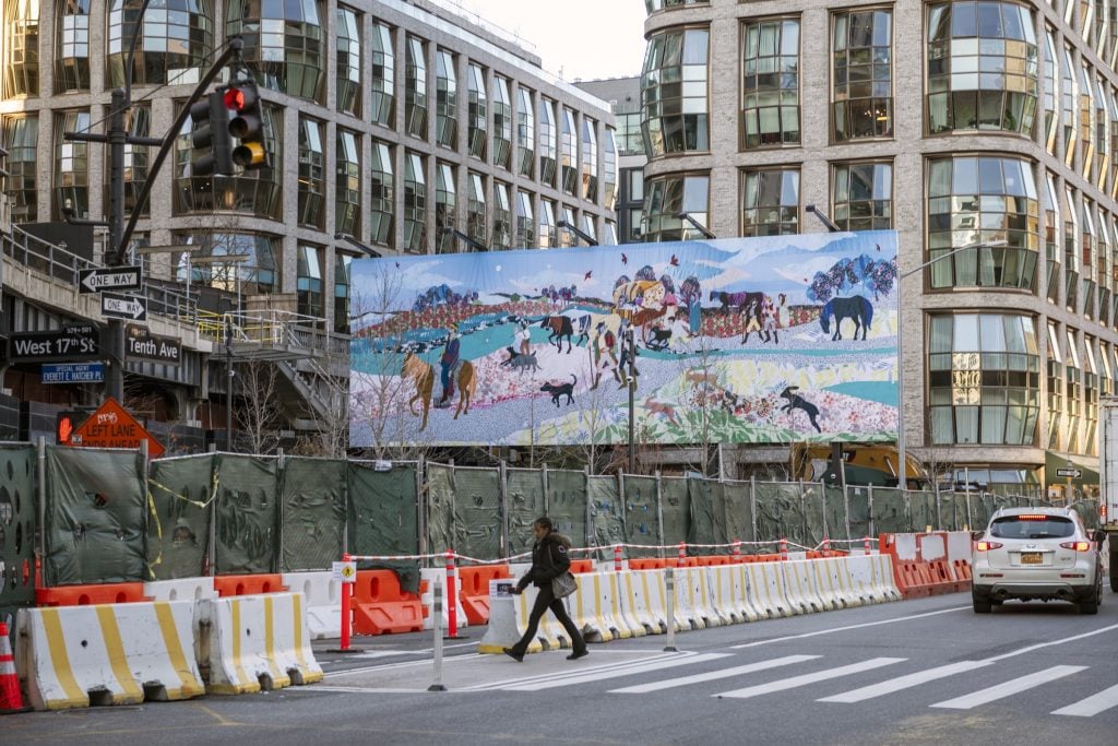 Małgorzata Mirga-Tas, Beyond the Horizon. A colorful quilted collage of a migrating Roma community, but depicted in an idealized fashion, reappropriating historical imagery that negatively stereotyped the ethnic group. It is seen on a billboard in New York City, with construction barriers on the street below it and multistory buildings behind it. 