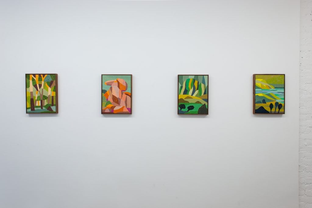 four landscape paintings are on a gallery wall 