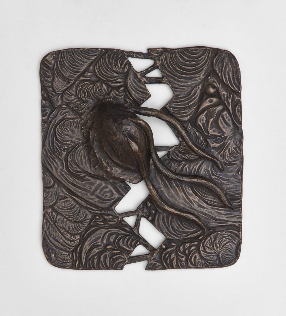 A Helen Evans Ramsaran bronze relief sculpture in the shape of a broken tablet, with a the shape of a growing seed in the center. 