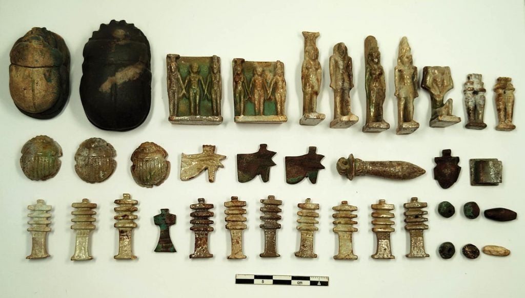 three rows of ancient Egyptian amulets and scarabs