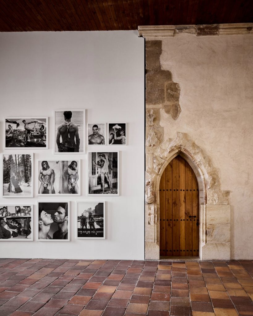 A rustic room blending modern black-and-white portrait photography with medieval stone architecture and wooden door.