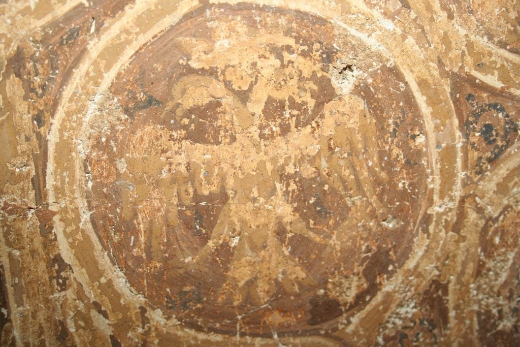 A close-up photograph of a 15th century fresco showing Emperor Constantine XI Palaiologos' medal.