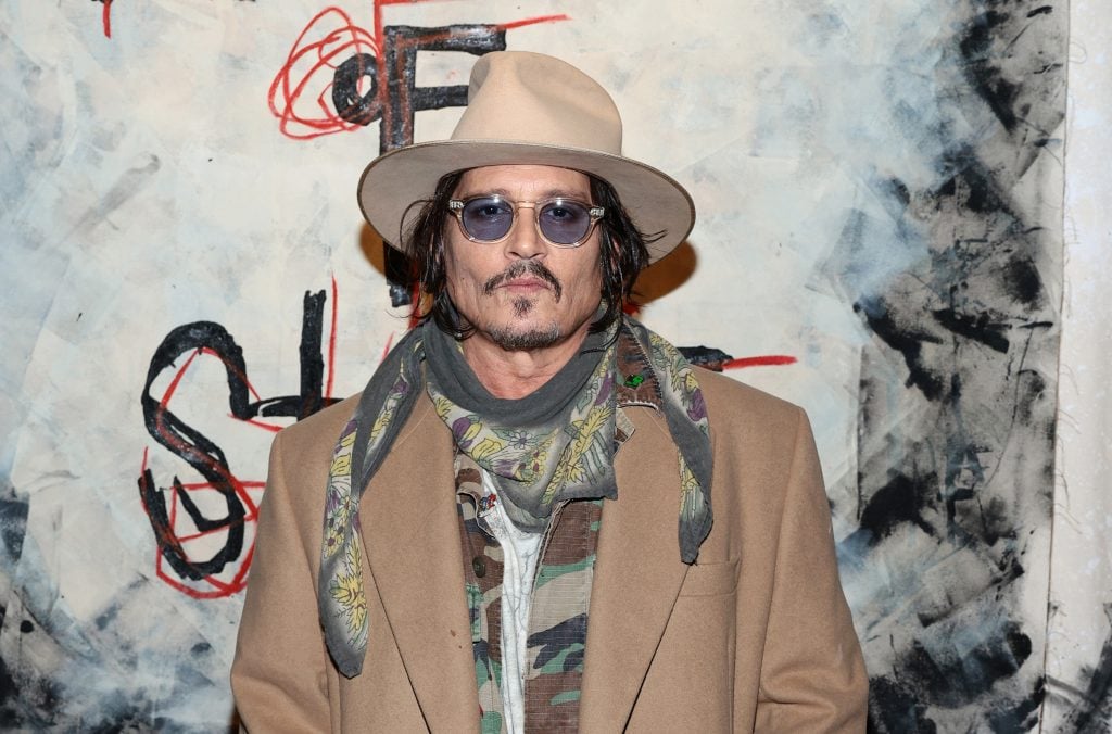 Actor Johnny Depp in a hat, sunglasses, and beige trench coat