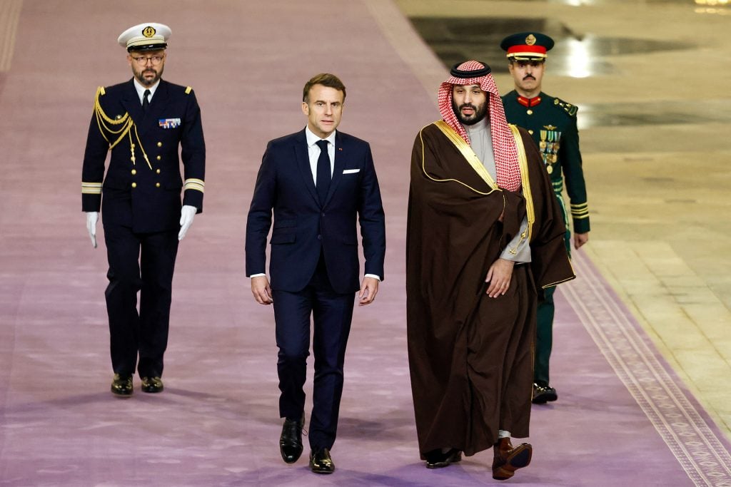 An image of French President Emmanuel Macron, second from left, walks next to Saudi's Crown Prince Mohammed Bin Salman, second from right