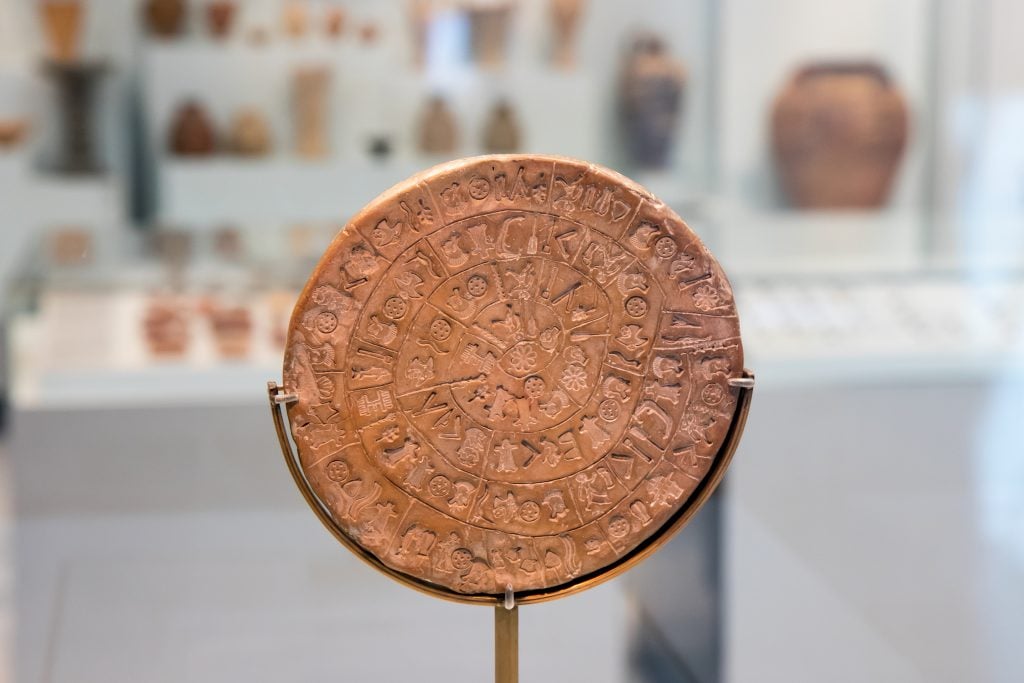 An ancient disk carved with hieroglyphics on view in a gallery